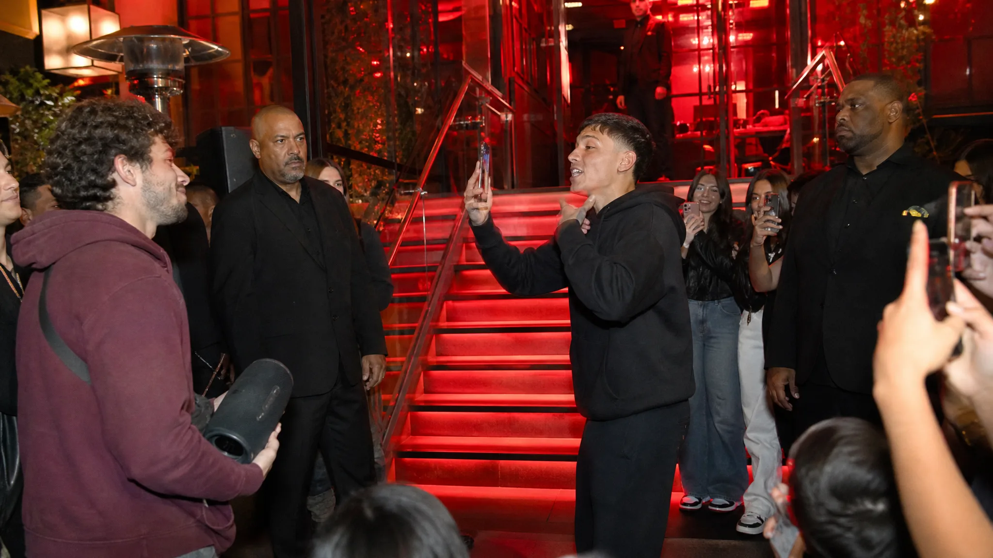 Red Stairs and Phones Up Wide night view of glowing red stairs, a man in a black hoodie rapping into his phone and fans holding phones up